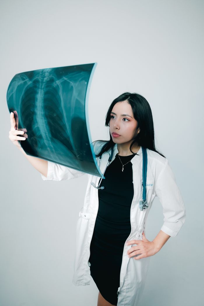 Young female doctor examining a chest X-ray with focus and professional attire.