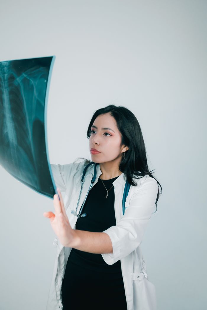 A female doctor examines an X-ray image thoughtfully, conveying professionalism and focus.