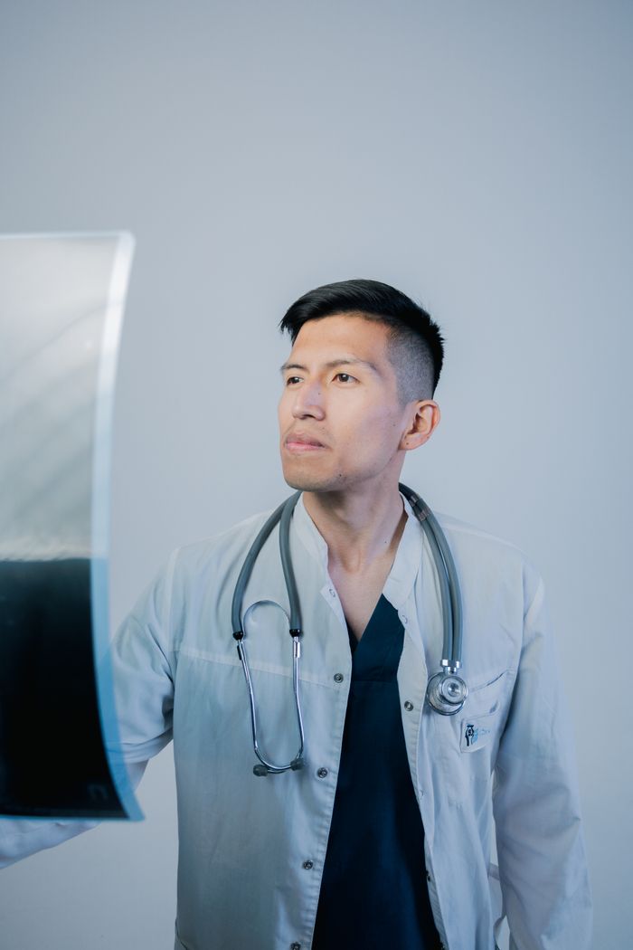 A focused doctor examines an X-ray image in a clinical setting, displaying professionalism.
