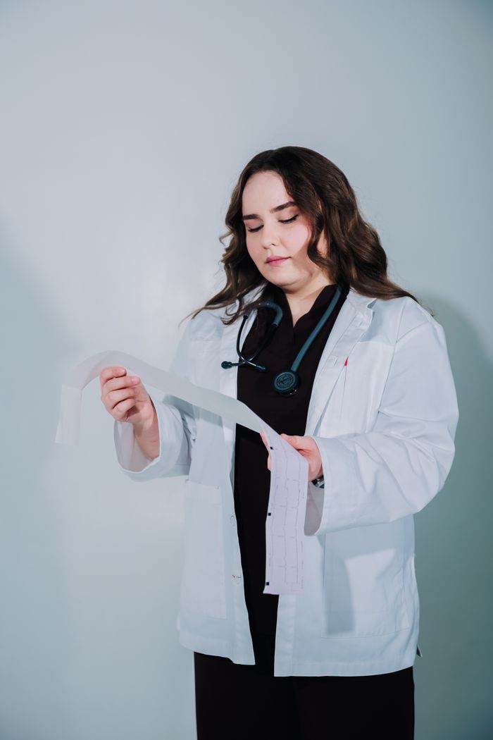 A female doctor examines a medical report in a clinical setting.