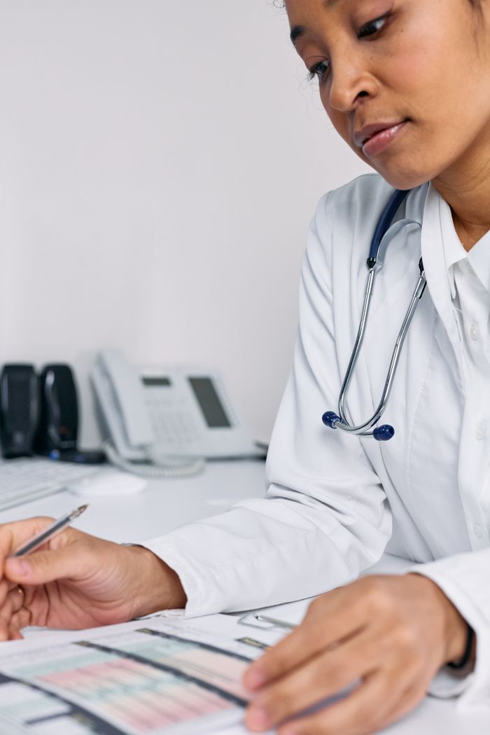 Doctor analyzing patient records at desk with medical tools visible.